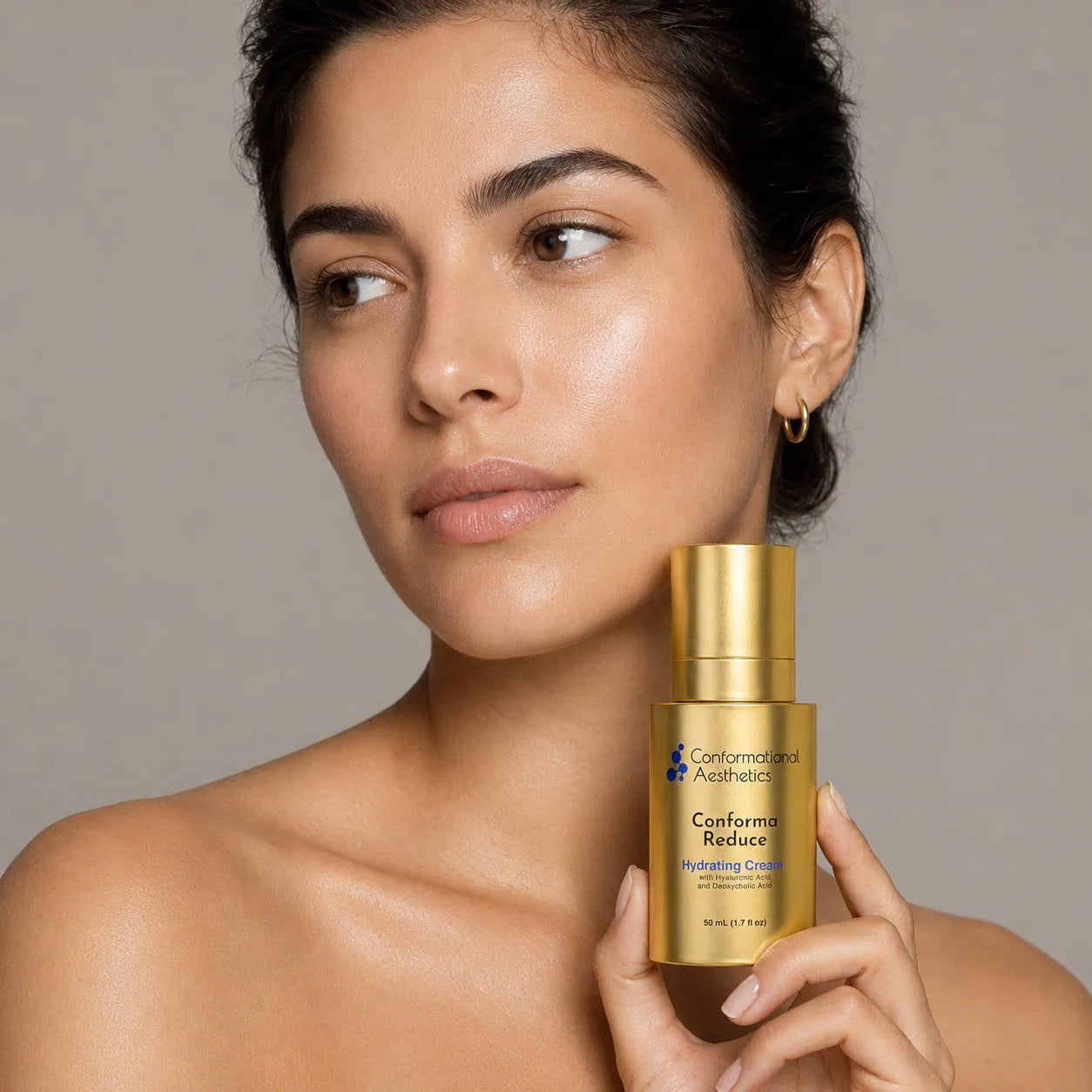 Woman holding a Conforma Reduce bottle beside her face.