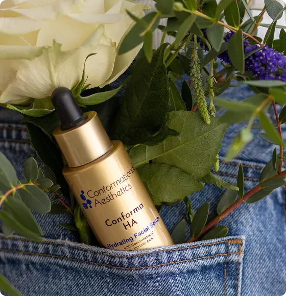 Conforma HA Hydrating Facial Serum surrounded by flowers and botanical greenery.